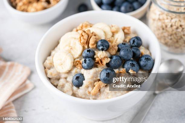 porridge oatmeal with banana blueberry walnut - oatmeal stock pictures, royalty-free photos & images