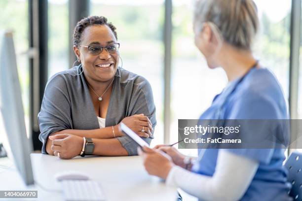 african woman at a medical appointment - mature women talking stock pictures, royalty-free photos & images