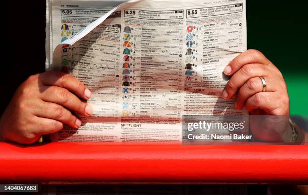 Spectator checks race information and odds in the newspaper during the Summer Evening Racing at Wolverhampton Racecourse on June 20, 2022 in...