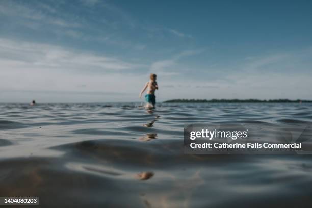 soft focus, dreamy image of a child playing in shallow water. the lake provides a space for copy. - 9 loch stock pictures, royalty-free photos & images