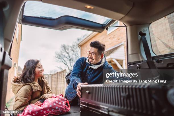 lovely girl assisting her daddy loading the bag & suitcase to the car trunk for their road trip - 日常の一コマ ストックフォトと画像