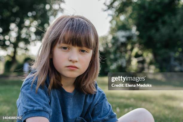 portrait of a girl of ten years in nature in the park. the girl looks at the camera and does not smile - 8 9 years fotos stockfoto's en -beelden