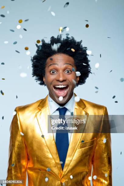 happy man amidst confetti against blue background - gold coat stock pictures, royalty-free photos & images