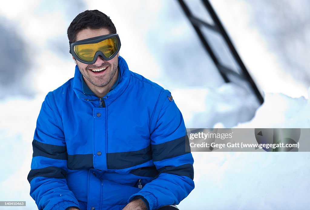 Smiling teenager on snow with blue jacket