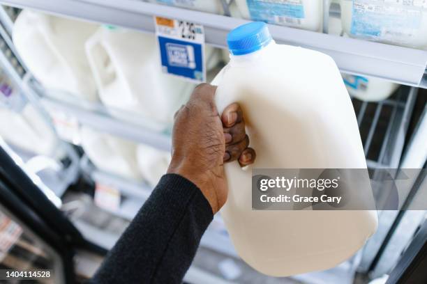 woman picks up gallon of milk at supermarket - galón fotografías e imágenes de stock