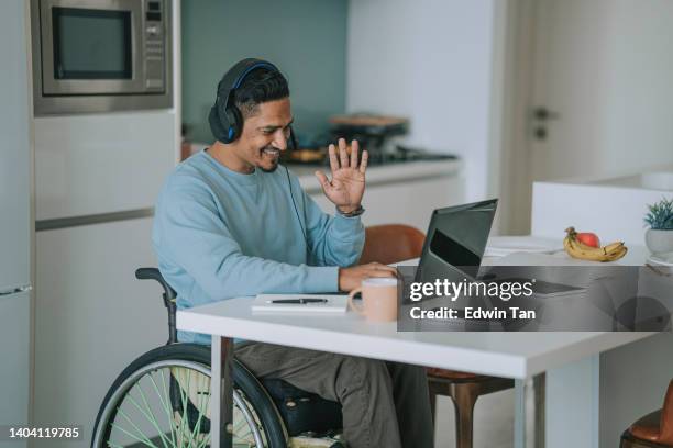 asia indian with disability  sitting on wheelchair in dinning room video call with laptop - wheelchair happy stock pictures, royalty-free photos & images