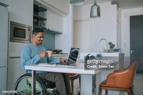 hombre indio asiático con discapacidad que trabaja en casa escribiendo usando una computadora portátil sonriendo - elearning man fotografías e imágenes de stock
