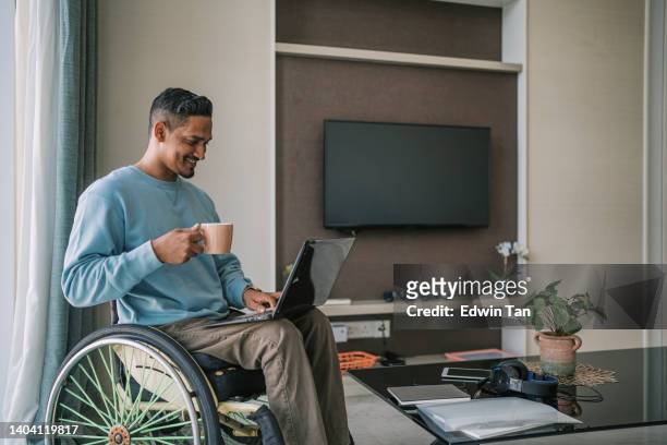 asia indian with disability sitting on wheelchair with laptop in living room reading mail from laptop smiling - man watching tv alone imagens e fotografias de stock