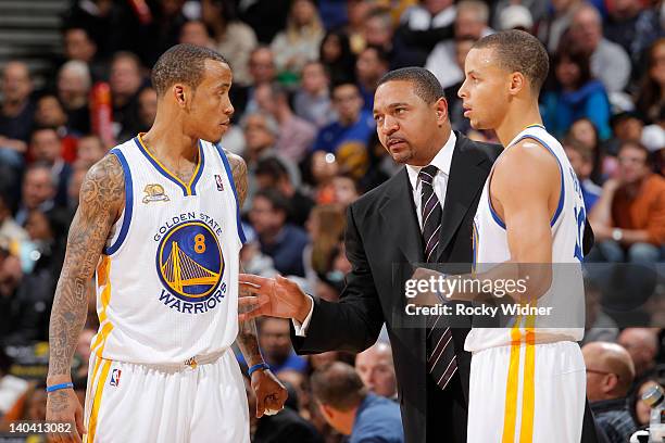 Head Coach Mark Jackson meets with Monta Ellis and Stephen Curry of the Golden State Warriors during a game against the Los Angeles Clippers on...