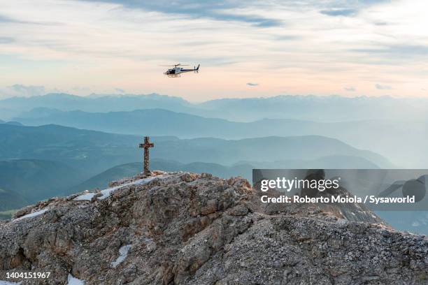 helicopter flying over dolomites mountains at sunset - gipfelkreuz stock-fotos und bilder