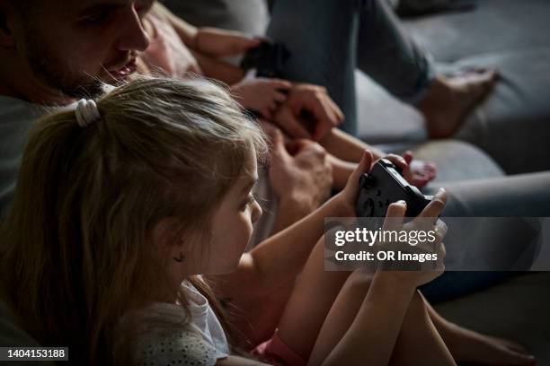 father with daughter holding game controller at home - game three stockfoto's en -beelden