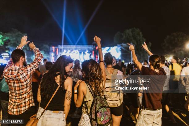 rückansicht von glücklichen frauen, die sich nachts auf einem musikfestival unterhalten. - popular music concert stock-fotos und bilder
