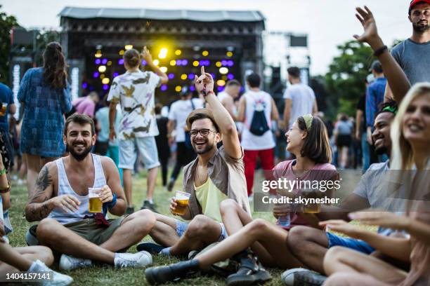 young friends relaxing on grass during music festival. - music concert stock pictures, royalty-free photos & images