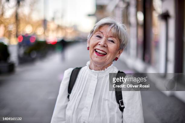 portrait of happy senior woman in the city - eine seniorin allein stock-fotos und bilder