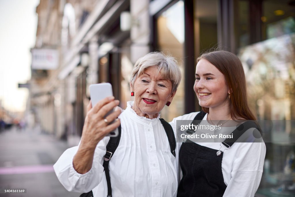 Grandmother and adult granddaughter taking a selfie in the city