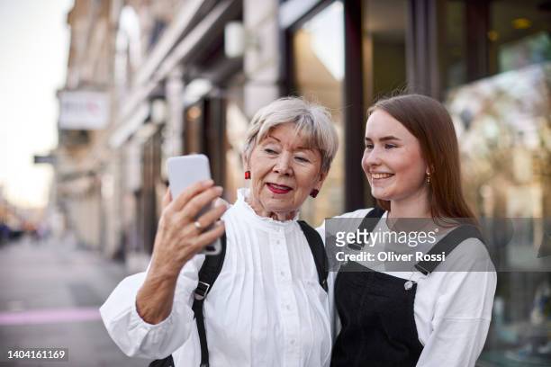 grandmother and adult granddaughter taking a selfie in the city - granddaughter stockfoto's en -beelden