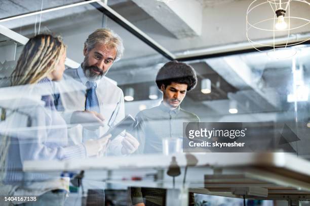 mature manager using touchpad with his young colleagues in the office. - marketing material stock pictures, royalty-free photos & images