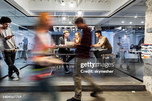 Jeunes gens créatifs travaillant dans le bureau parmi les personnes dans le mouvement flou. Jeunes gens créatifs travaillant dans le bureau parmi les personnes dans le mouvement flou.