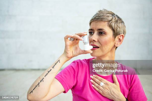 schöne reife frau, die asthma mit inhalator behandelt - patientin stock-fotos und bilder