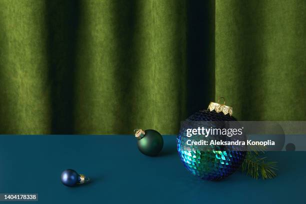 dark blue christmas ornament on solid blue background with folded green velvet backdrop - christmas still life fotografías e imágenes de stock