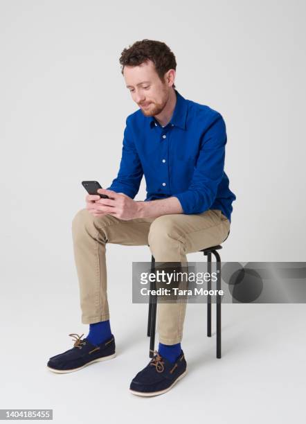 man looking at phone - sitting and using smartphone studio stock-fotos und bilder