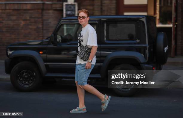 Erik Scholz seen wearing a brown sunglasses, a white cotton logo shirt from Axel Arigato, a pearl necklace, a light bluse denim shorts from Zara, a...