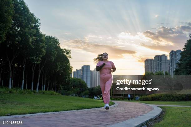 散歩道で公園を走っている太りすぎの女性。 - human build ストックフォトと画像