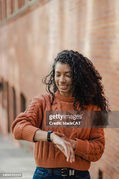 charmante jeune femme afro-américaine utilisant une montre intelligente dans la rue - podomètre photos et images de collection