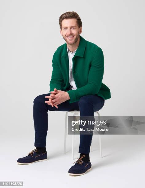 man sitting an doling to camera - stool stockfoto's en -beelden