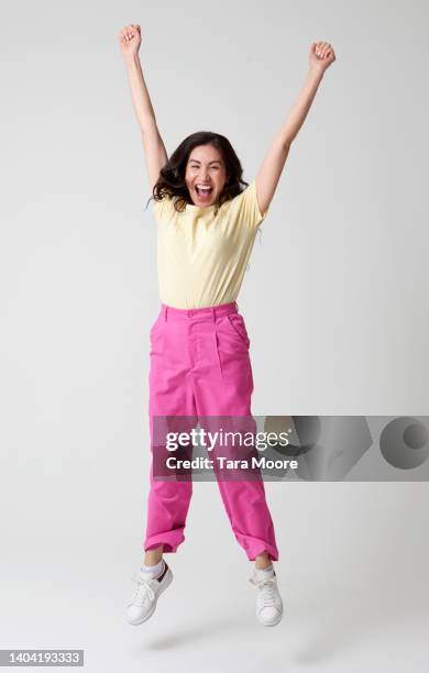 woman jumping for joy - alzar los brazos fotografías e imágenes de stock