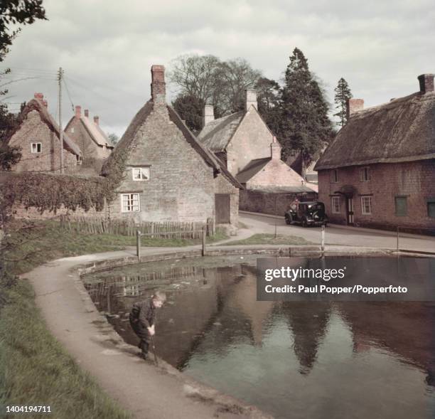 Child plays beside a pond in the centre of the village of Wroxton near Banbury in Oxfordshire, England circa 1960.