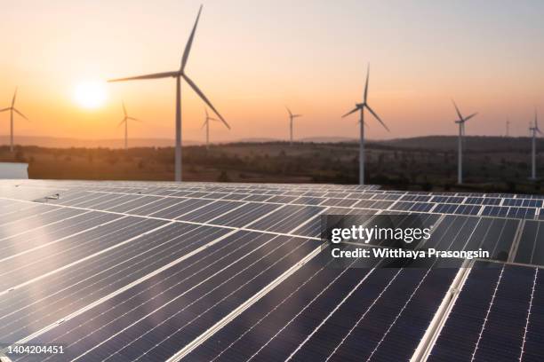 solar panels and wind generators under blue sky on sunset - solarpark stock-fotos und bilder