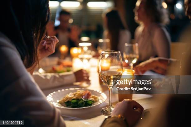 irreconocibles amigos multirraciales femeninos y masculinos, cenando en el balcón del restaurante - dinner party fotografías e imágenes de stock