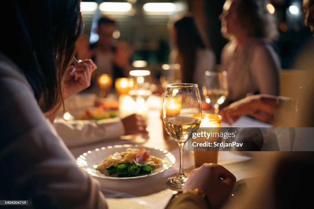 Amici femminili e maschili multirazziali irriconoscibili, che cenano sul balcone del ristorante