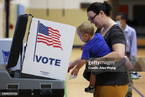 Voter casts her ballot with her child at a polling station at Rose Hill Elementary School during the midterm primary election on June 21, 2022 in...