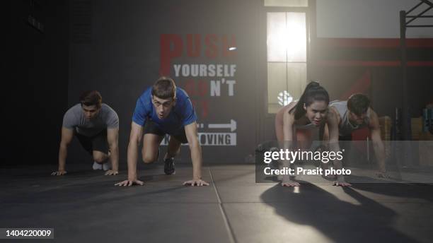 group of friends doing mountain climber workout on floor of gym - hiit stock-fotos und bilder