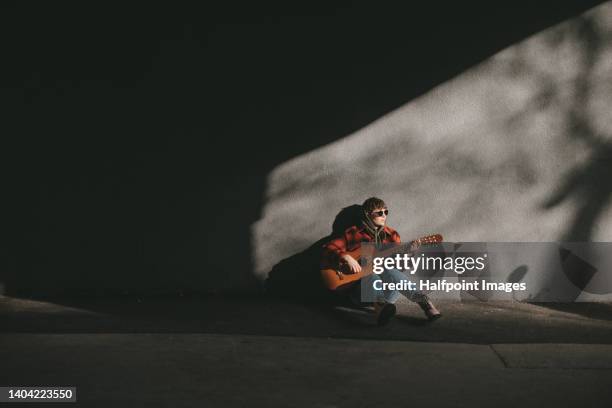 young woman with short hair playing on the guitar in the street. - ukelele stock pictures, royalty-free photos & images