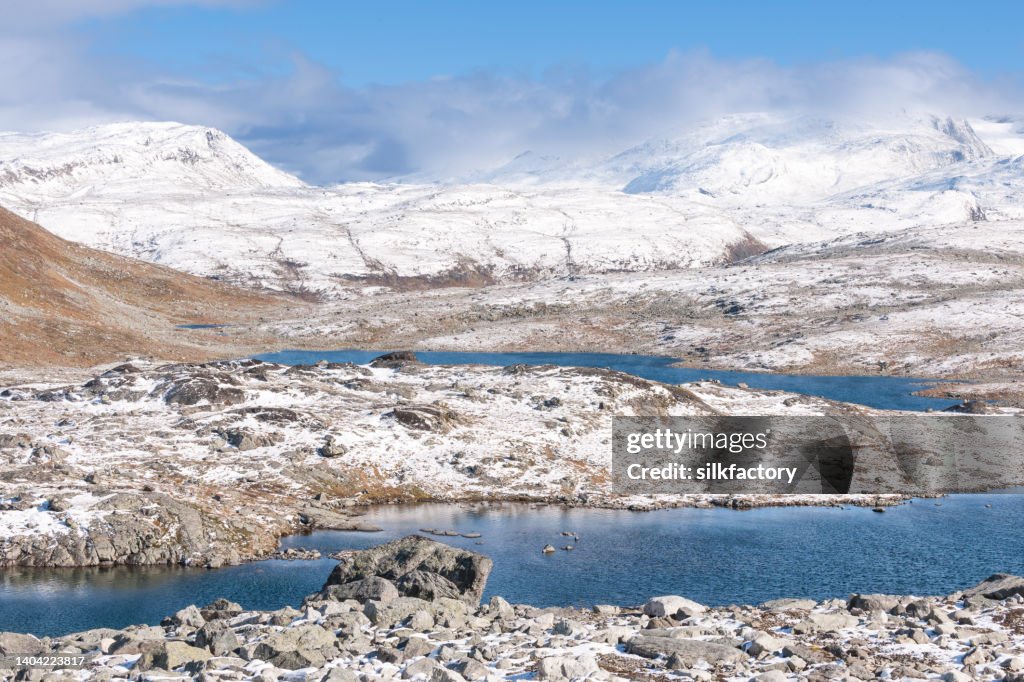 A primeira neve da estação no outono ao longo da trilha rochosa em altas montanhas da Noruega