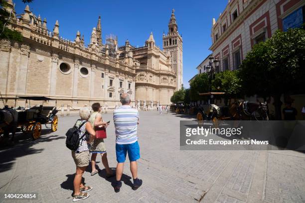 Three tourists look attentively at the Giralda from the Plaza del Triunfo on June 21, 2022 in Seville .