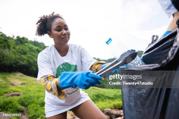 young black woman joined as nature saver volunteers picking up litter on the mountain - müllsack stock-fotos und bilder