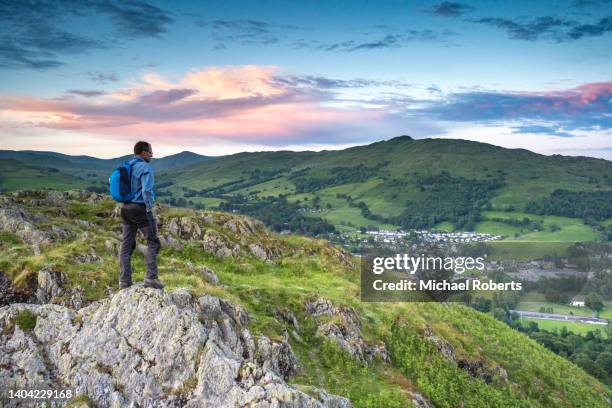 walker on loughrigg fell looking towards ambleside in the lake district national park - loughrigg fell stock pictures, royalty-free photos & images