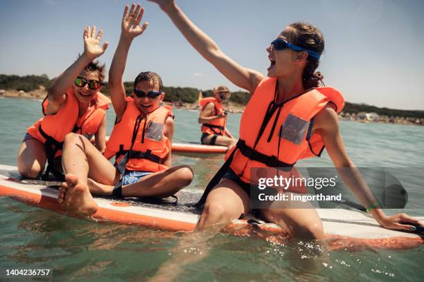 family enjoying paddle boarding on sup - season 14 stockfoto's en -beelden