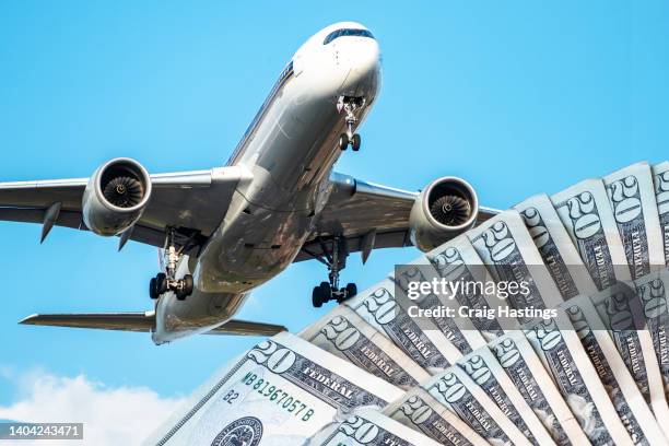 airplane in mid flight with a selection of us dollar currency notes. concept piece to show increase in flight and operating costs in the aviation industry due to rising oil and fuel prices along with supply chain issues. - economic cartel stock pictures, royalty-free photos & images