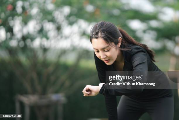 young asian sports woman check performance on  smartwatch after run. - marathon zuschauer stock-fotos und bilder