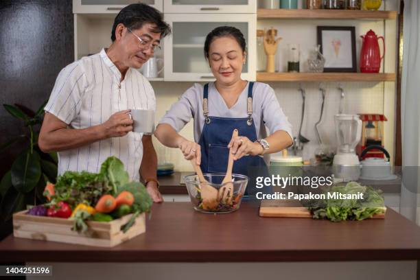 senior asian couple love cooking together in the kitchen with happiness at home. - asian couple dinner stock pictures, royalty-free photos & images