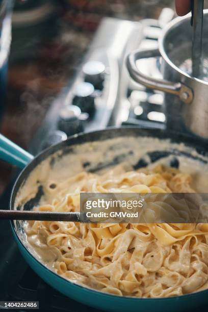 preparing fettuccine pasta alfredo with parmesan - fettuccine alfredo stock pictures, royalty-free photos & images