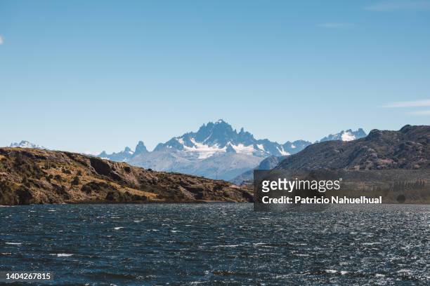 large patagonian mountain range behind a navy blue lake. - aysén del general carlos ibáñez del campo stock pictures, royalty-free photos & images
