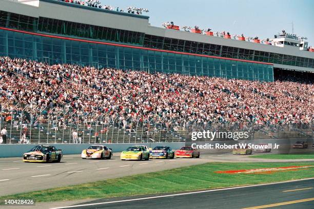 View of the stands and the racecars speeding by as 180,000 fans attend the Winston Cup Race at the Charlotte Motor Speedway, Charlotte, NC, 1998. On...