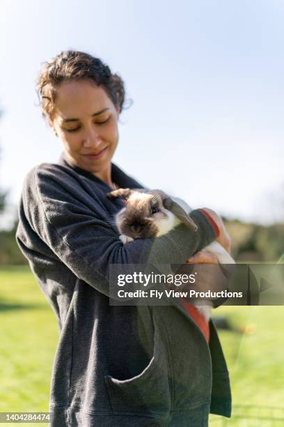 beautiful woman snuggling pet rabbit outside - hawaiian women weaving stock pictures, royalty-free photos & images