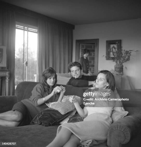 Italian actress Lucia Bose with Franco Interlenghi and Antonella Lualdi sitting on a sofa and smoking a cigarette, Madrid, 1961.